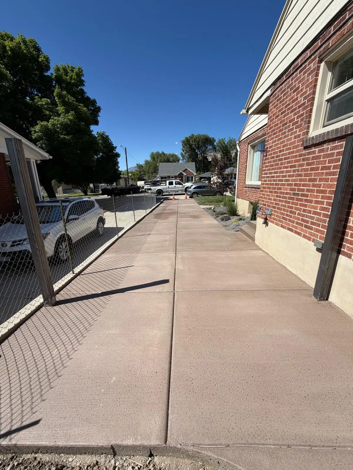Integrally colored concrete driveway running along a brick home