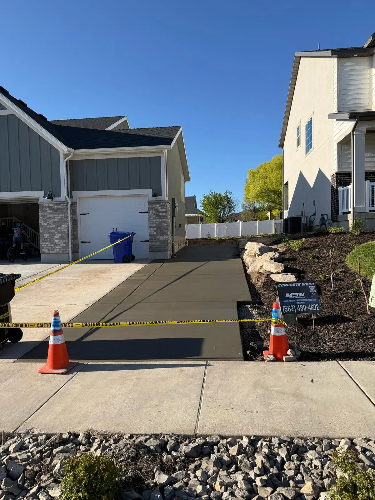Freshly poured driveway extension curing beside a residential garage