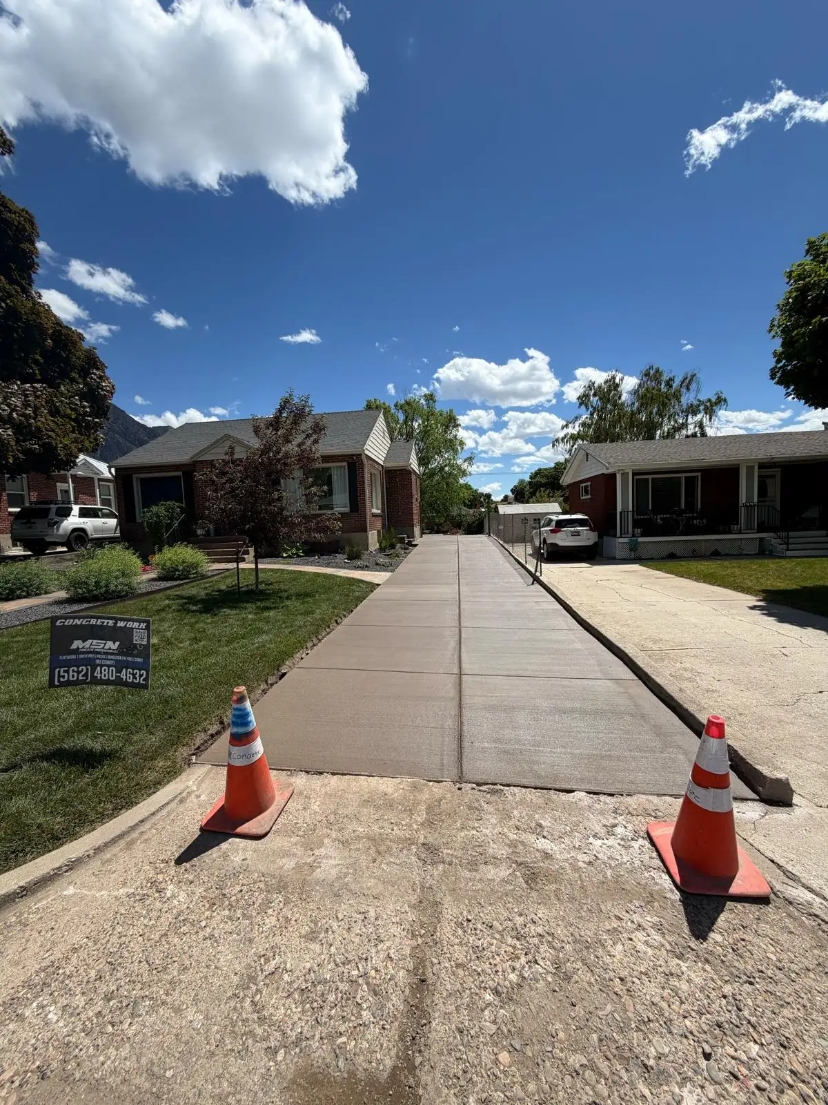 Long residential concrete driveway replacement between two brick homes in Ogden